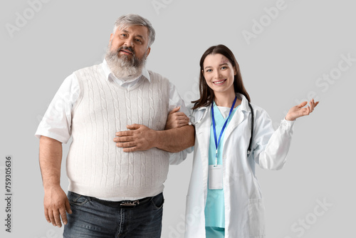 Mature man with nurse holding hands on light background © Pixel-Shot