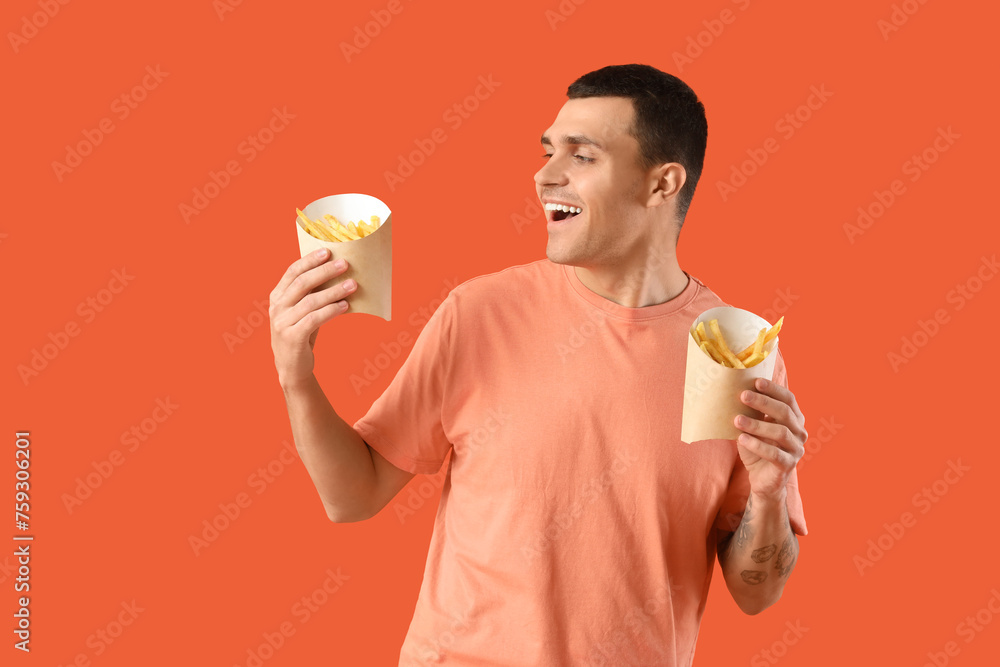 Fototapeta premium Young man with french fries on orange background