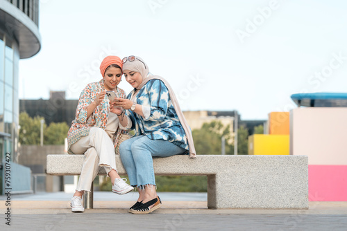 Portrait of happy muslim women friends using phone photo