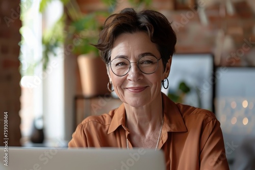 Smiling mid aged business woman in office looking at laptop computer