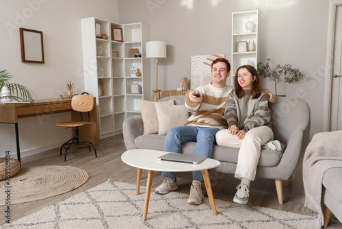 Young couple on sofa watching TV in living room