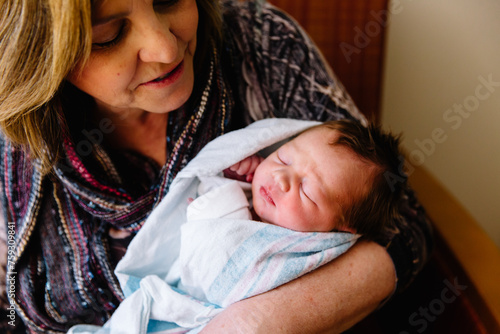 Grandmother holding newborn baby in hospital bed