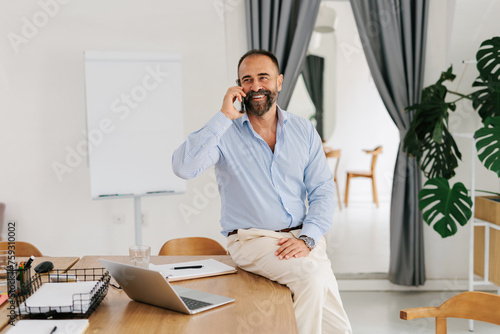 Portrait of adult businessman using smartphone in office  photo
