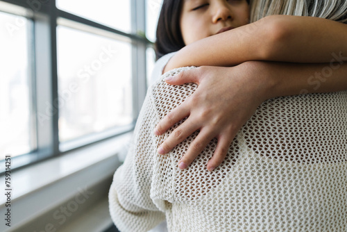 A girl with her mother hugging at home photo