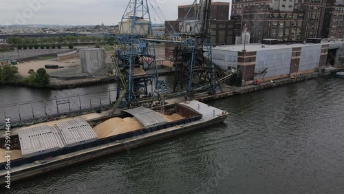 BALTIMORE - 1.19.2024 - Excellent aerial footage pulling away from a crane drawing sugar from a ship's hold to a waterfront refinery in Baltimore, Maryland.