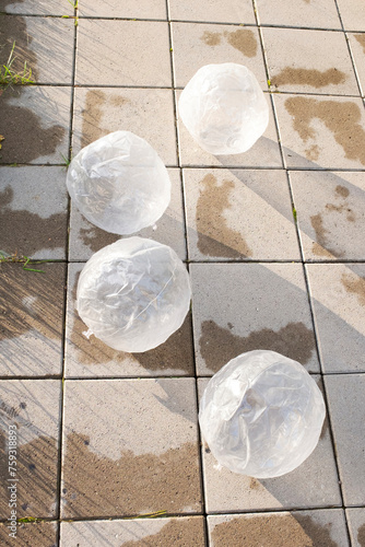 Clear plastic transparent balls lying on a tile pavement in garden  photo