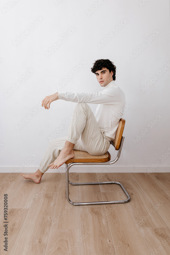 Stylish man sitting on chair in light studio Stylish man sitting on chair in light studio