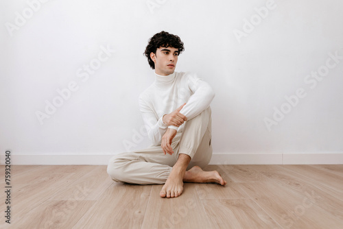 Stylish man sitting on parquet floor in light room photo