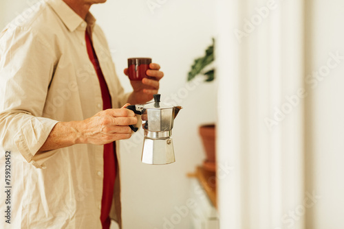 Man holding moka pot and coffee cup photo