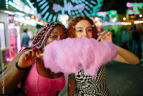 Two young girls having cotton candy at a fair