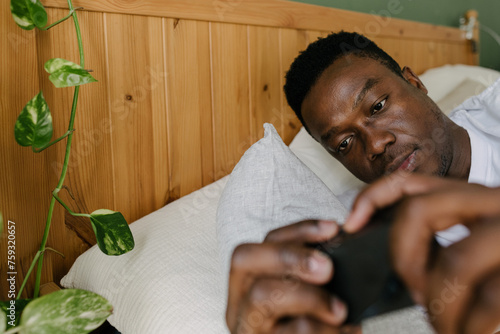 A man in bed switching off his alarm clock photo