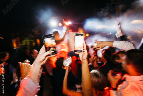 two hands holding phones in a party photo
