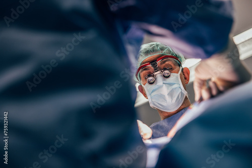 Doctor in magnifying glasses performing surgery at clinic photo