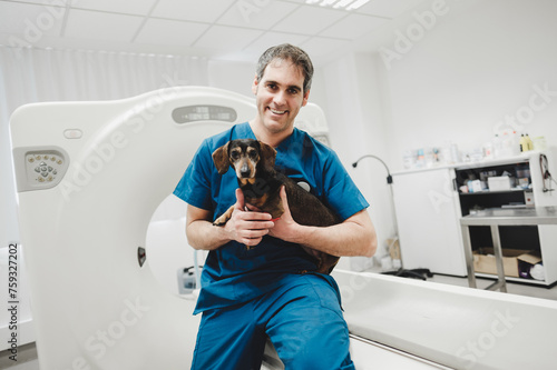 Cheerful Veterinarian holding Dachshund near tomograph