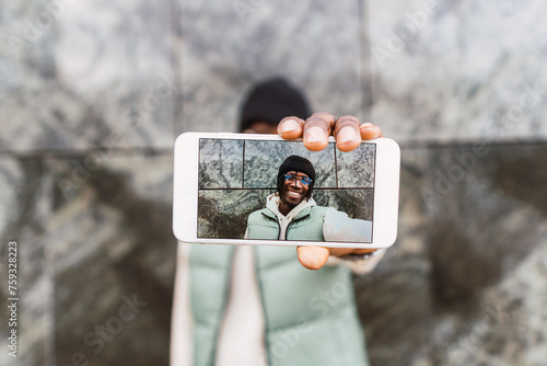 Positive black man taking selfie on smartphone photo