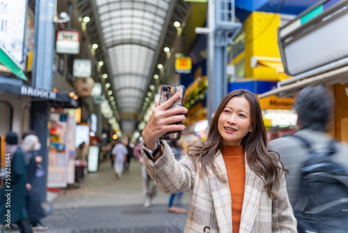 Happy Asian woman using mobile phone taking selfie during travel Sensoji Temple at Asakusa district, Tokyo, Japan. Attractive girl enjoy urban outdoor lifestyle travel city street on holiday vacation. photo