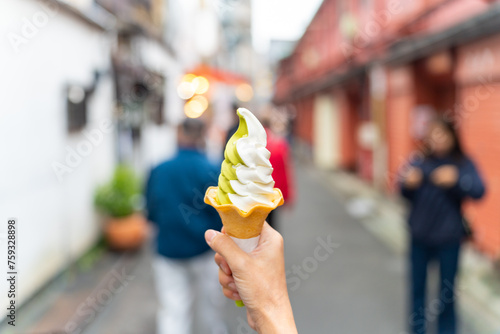Asian woman hand holding soft serve cone ice cream during travel at Asakusa district, Tokyo, Japan. People enjoy and fun outdoor lifestyle travel and shopping in the city on holiday vacation. photo