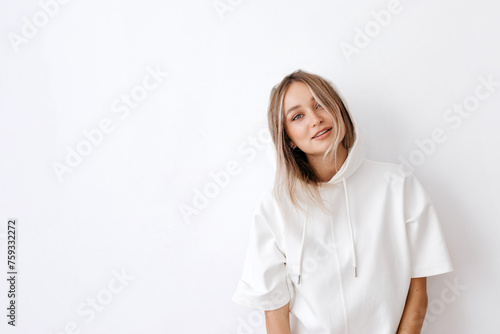 Happy young woman in white hoodie in studio photo