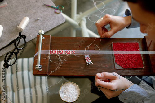 a woman weaves a bracelet from beads photo