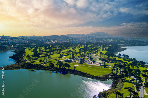 aerial shot of a beautiful spring landscape at Lake Merced with blue lake water and lush green trees, grass and plants at sunset in San Francisco California USA