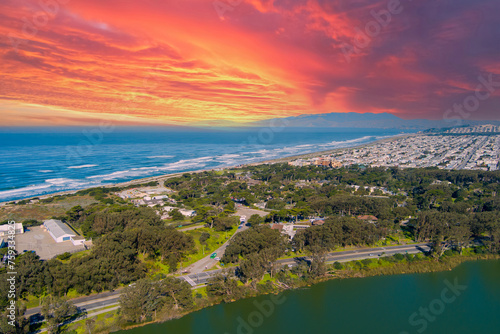 aerial shot of a beautiful spring landscape at Lake Merced with vast blue ocean water a sandy beach, green trees and grass and cars on the street in San Francisco California USA photo