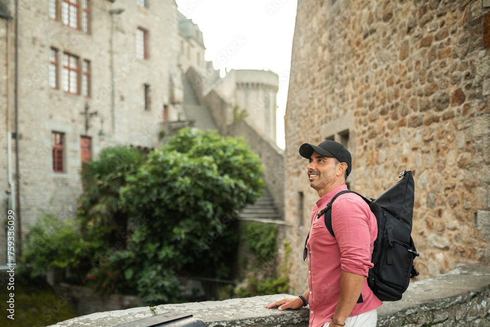 tourist man walking through mont saint michel with his backpack tourist man walking through mont saint michel with his backpack