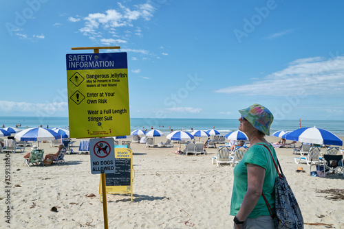 Beach Safety sign being read by tourist photo