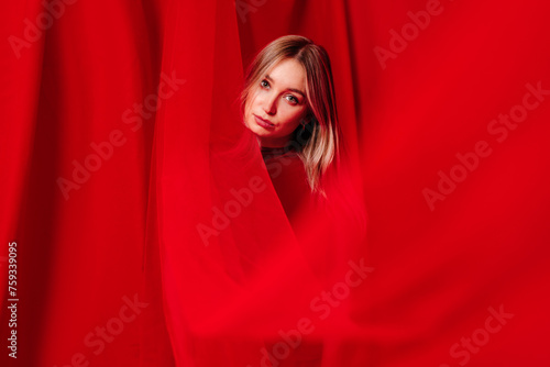 Charming fair haired lady in split of hanging red cloth photo