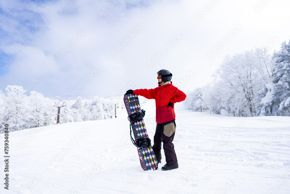 Naklejka premium Young Asian woman enjoy outdoor active lifestyle winter extreme sport training freeride snowboarding on holiday vacation. Attractive girl holding snowboard walking on snowy mountain at ski resort.