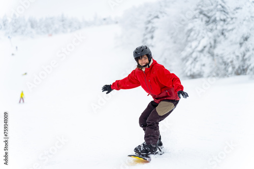Young Asian woman practice downhill sliding snowboard on snow mountain at ski resort. Attractive girl enjoy outdoor active lifestyle travel nature and winter extreme sport training on holiday vacation