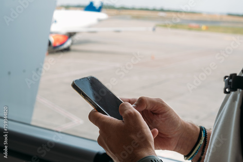 Cropped Image of Hands Holding Mobile Phone at Airport  photo