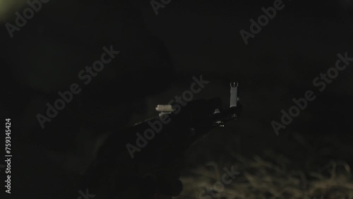 Soldier shoots at an enemy with a machine gun at night. Male soldier aims a machine gun at nigh. Night fight. Shooting from a machine gun on a dark background