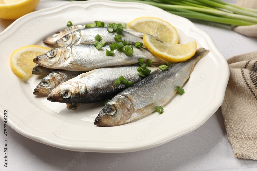 Fresh raw sprats, green onion and cut lemon on white table, closeup Fresh raw sprats, green onion and cut lemon on white table, closeup
