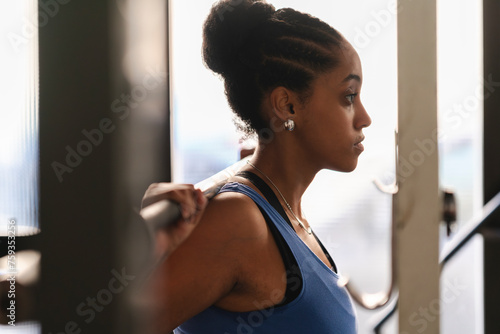 Young strong black woman doing exercise with barbell photo
