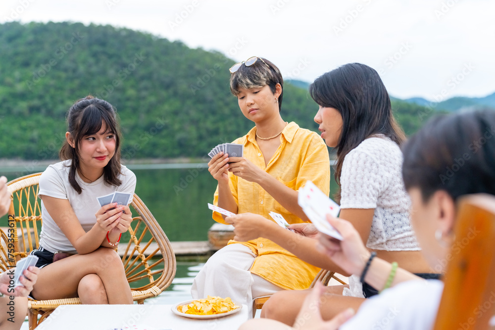 Group of Young Asian man and woman enjoy and fun outdoor lifestyle travel nature forest mountain on summer holiday vacation. Generation z people friends playing cards together on lake house balcony. Group of Young Asian man and woman enjoy and fun outdoor lifestyle travel nature forest mountain on summer holiday vacation. Generation z people friends playing cards together on lake house balcony.