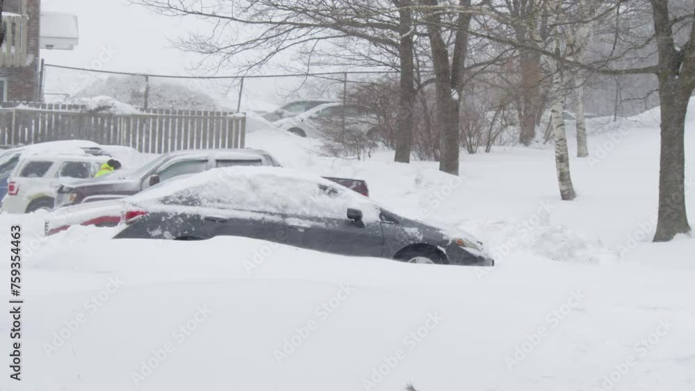 View of a snow storm covering cars and a parking lot near apartment buildings in Dartmouth, Canada. People go out into the street with shovels and shovel heaps of snow, digging cars out of the snow. View of a snow storm covering cars and a parking lot near apartment buildings in Dartmouth, Canada. People go out into the street with shovels and shovel heaps of snow, digging cars out of the snow.
