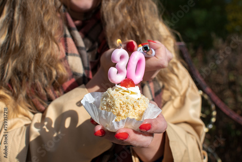 A birthday cupcake with pink 30th birthday numeral candle on top photo