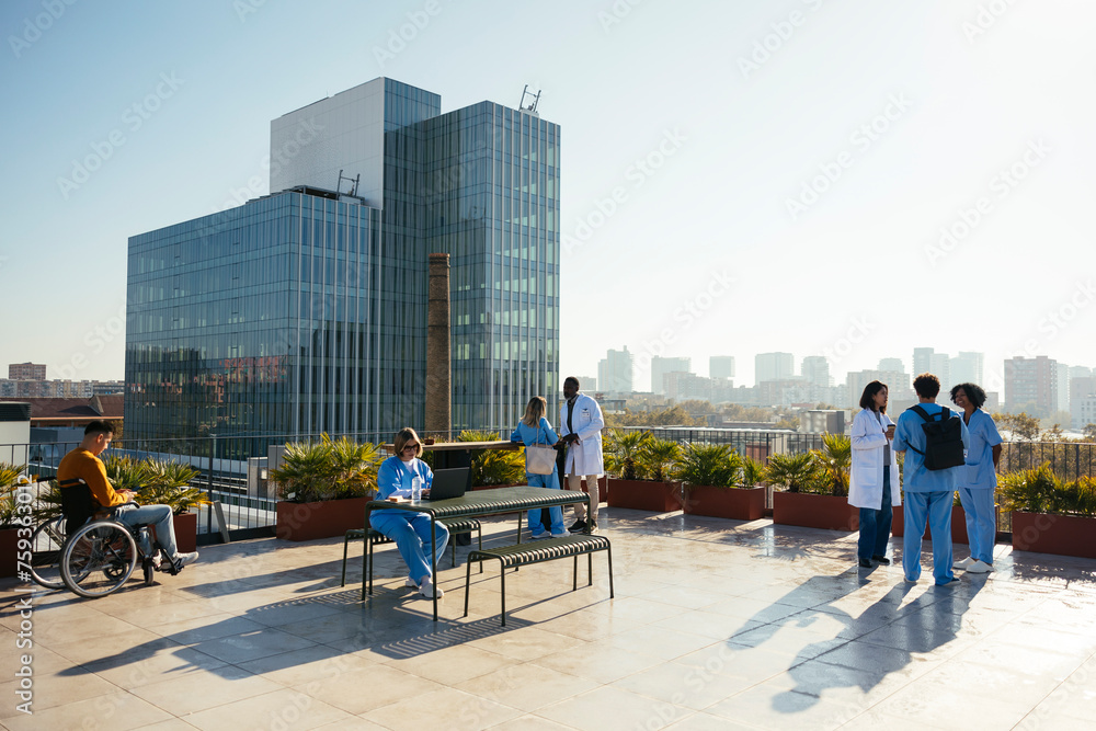© BONNINSTUDIO/Stocksy - Diverse medical team taking a break on hospital terrace © BONNINSTUDIO/Stocksy - Diverse medical team taking a break on hospital terrace
