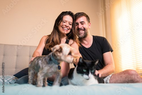 Cheerful couple with dog and cat on bed photo