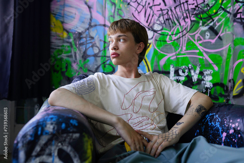 Young queer man sitting on armchair photo