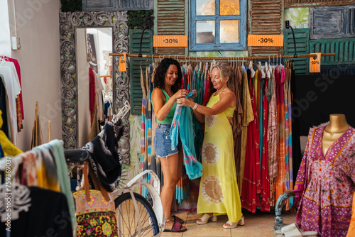 Happy women choosing dress in store shop photo