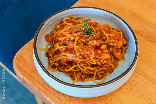 Spaghetti with tomato sauce on a plate on a wooden table ready to be served in a Thai restaurant.