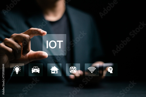 Smart business IOT, internet of things concept. Businessman touching IOT icon on virtual screen for connecting to internet to access AI artificial intelligence and business analysis.