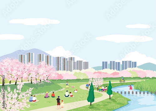 도심의 하천 산책로에 활짝 핀 벚꽃들과 소풍을 즐기는 사람들
