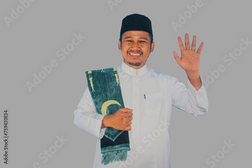 moslem man walking and waving hand to greet someone with happy expression photo