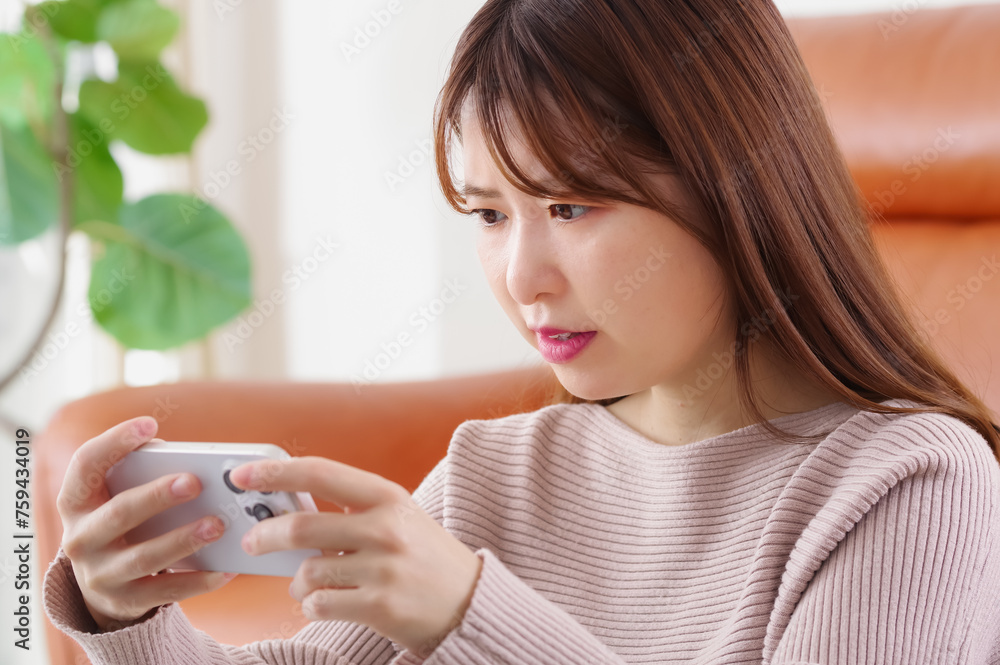 真剣な表情でスマートフォンを見つめる女性