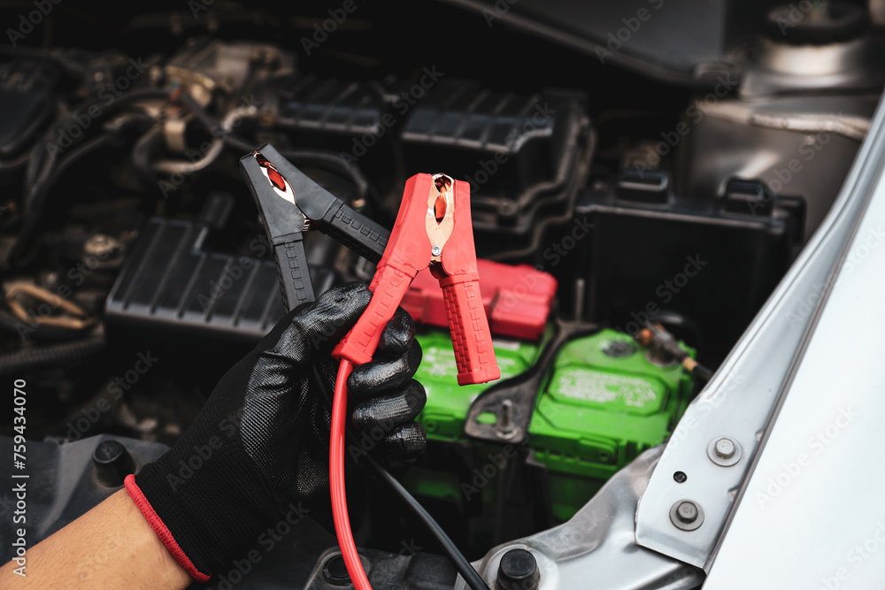 Hand car mechanic holding car booster cables for jump start car for empty battery dead and low voltage power problem or fix service maintenance accident assistance technician and energy charge. Hand car mechanic holding car booster cables for jump start car for empty battery dead and low voltage power problem or fix service maintenance accident assistance technician and energy charge.
