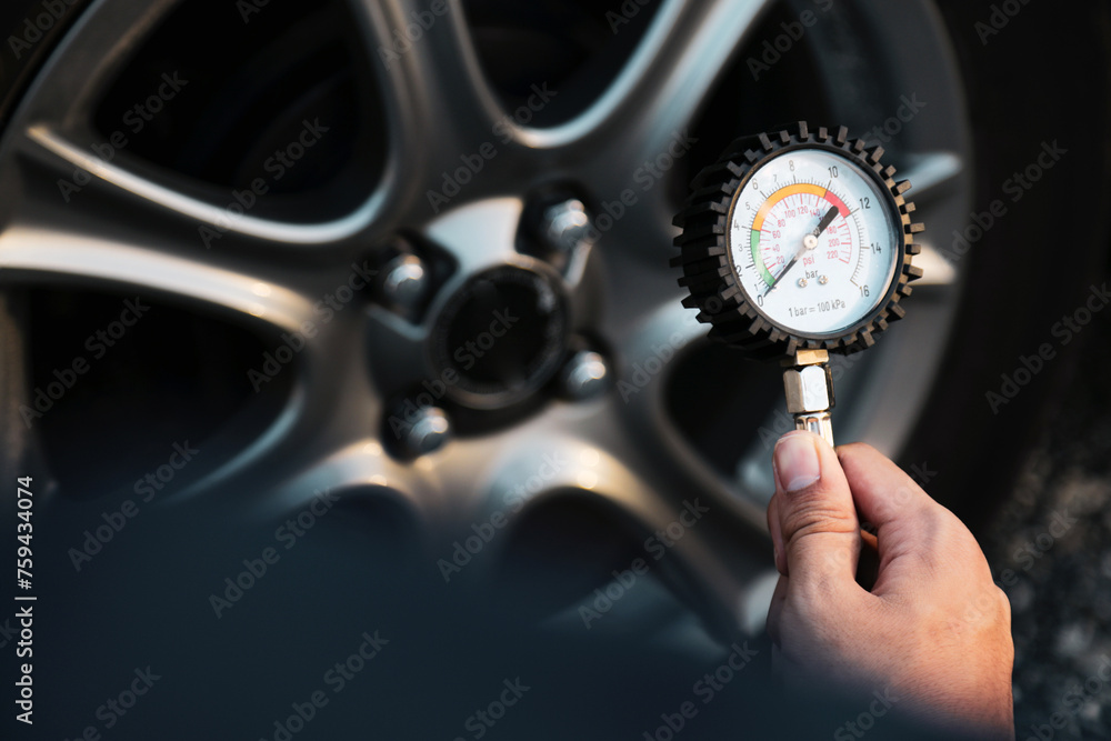 Hand car mechanic holding car tire pressure check equipment tool to checking low tire pressure inflating tires to or refill or air inflate to safety and car care service maintenance inspection. Hand car mechanic holding car tire pressure check equipment tool to checking low tire pressure inflating tires to or refill or air inflate to safety and car care service maintenance inspection.