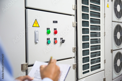 Electrical engineer checking electric at circuit breaker of air handling unit (AHU) starter control panel for air conditioner or load center cabinet for maintenance in main power distribution room.