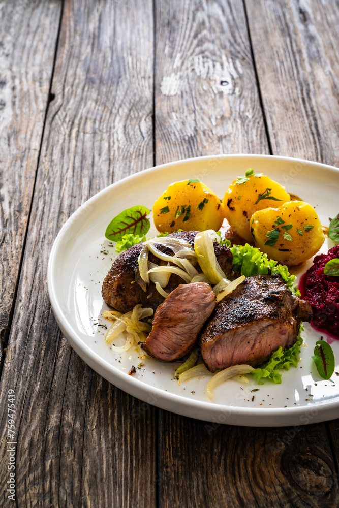 Baked pork cheeks with boiled potatoes and beetroots on wooden table
Baked pork cheeks with boiled potatoes and beetroots on wooden table